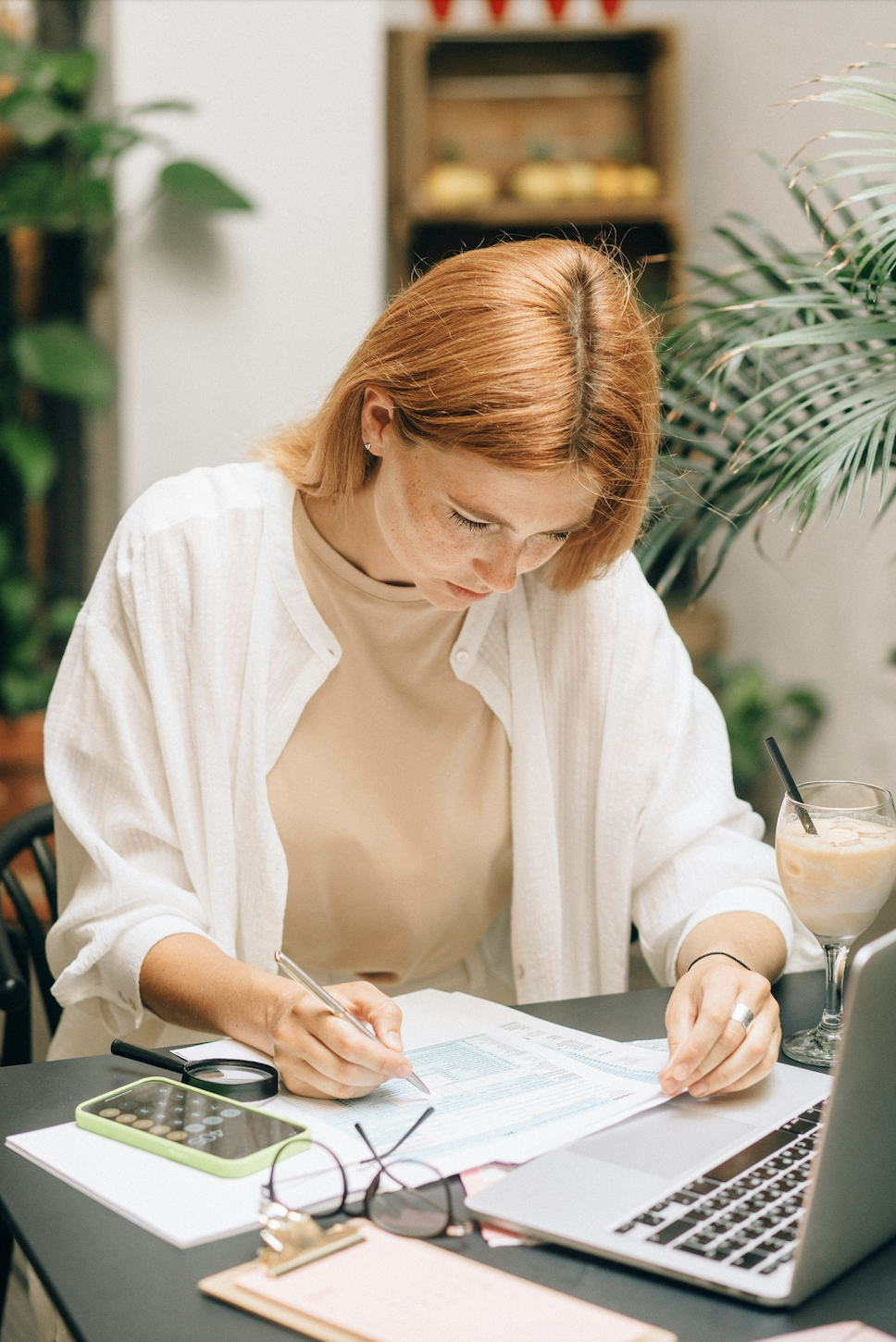 Person writing financial goals in a notebook with a coffee on the table.